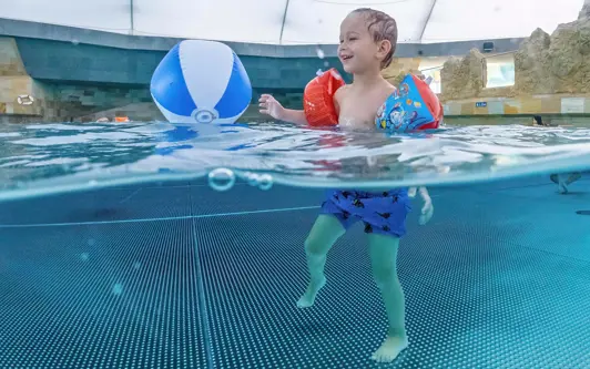 Child plays with ball in the wave pool of the Tamaro Splash and Spa